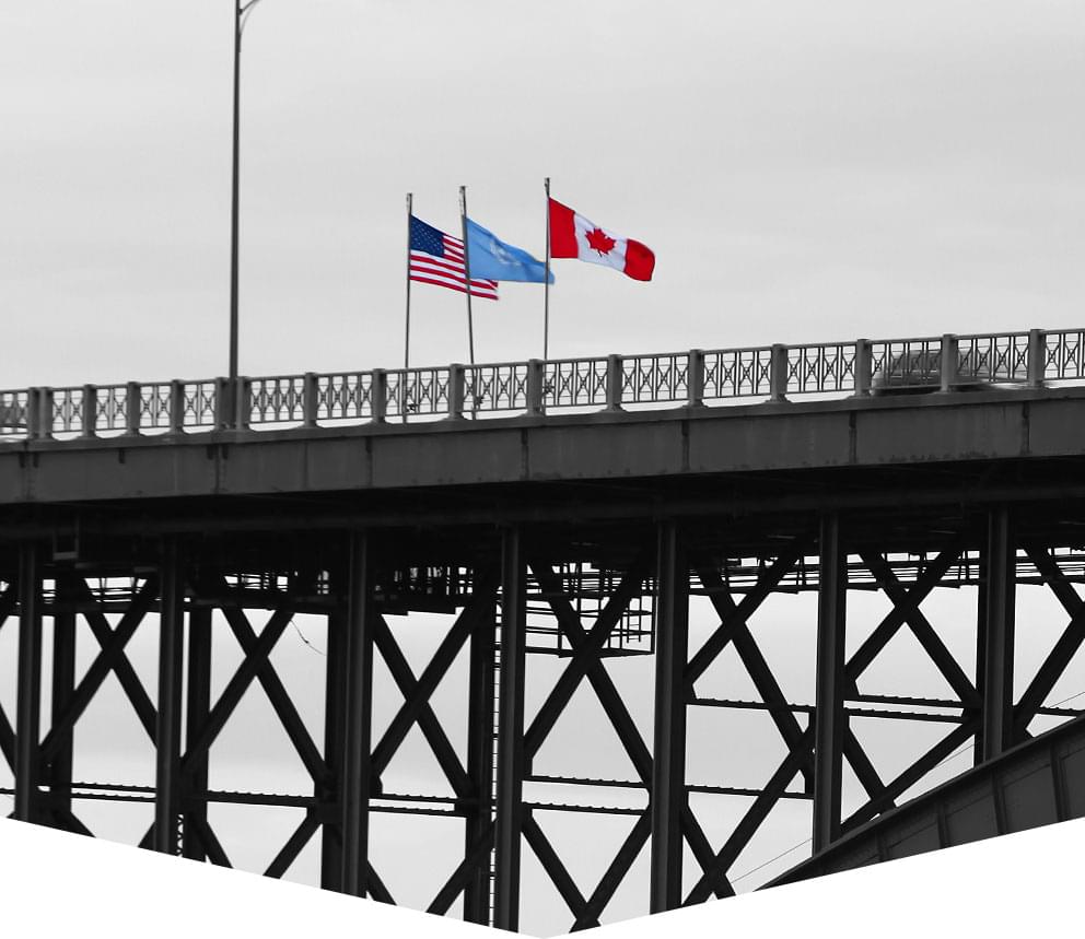 A border bridge crossing, with Canadian and American flags flying.