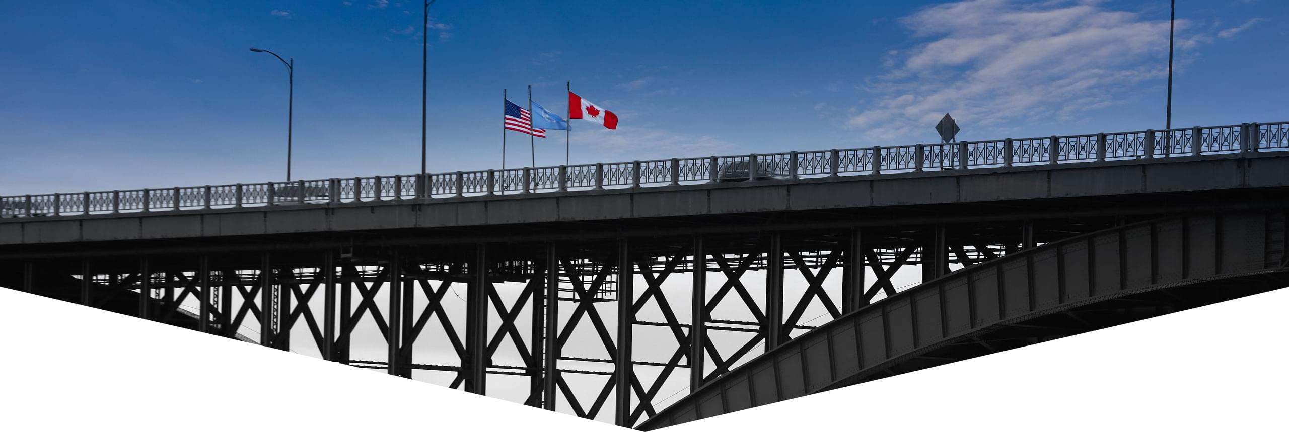 A border bridge crossing, with Canadian and American flags flying.